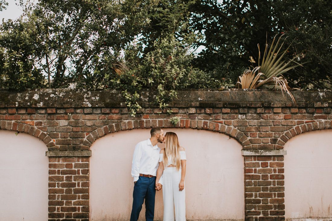 Couple embracing near a historic wooden door in downtown Charleston