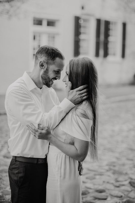 Bride and groom-to-be laughing together on historic Chalmers Street in Charleston, SC