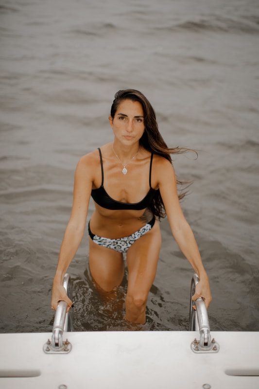 One of the Bikini Beach Australia models walking along the shoreline in bright, natural beach light