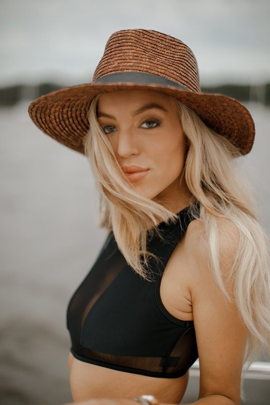 One of the shoot's three models laughing in the sun against warm sand and blue water