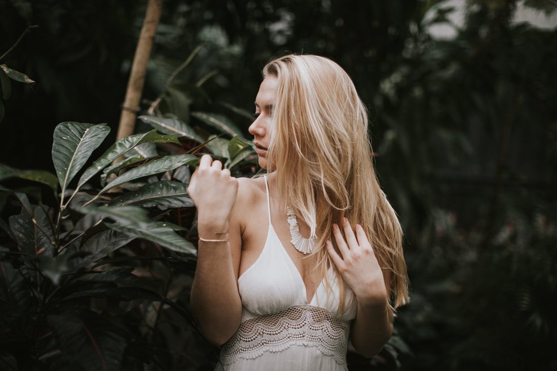 Portrait of Morgan surrounded by lush greenhouse foliage in Charleston