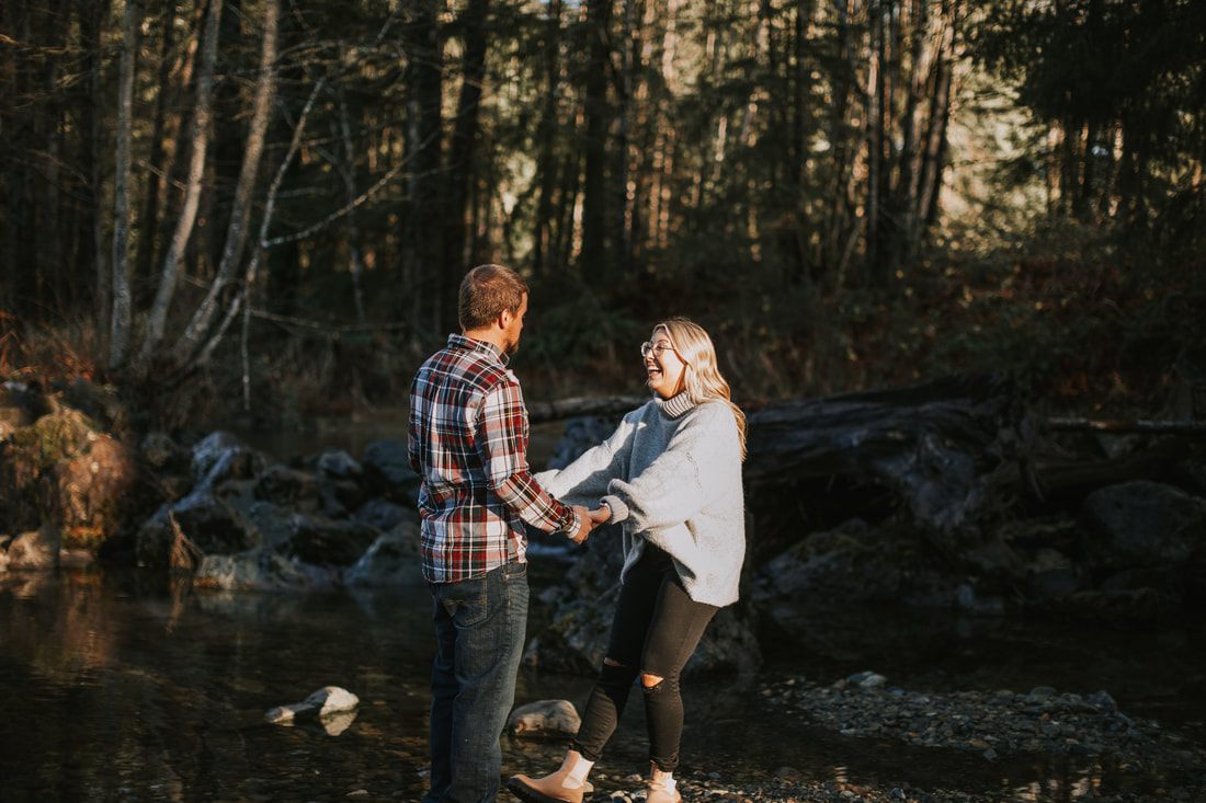 Couple holding hands while walking through tall grass in North Bend, WA
