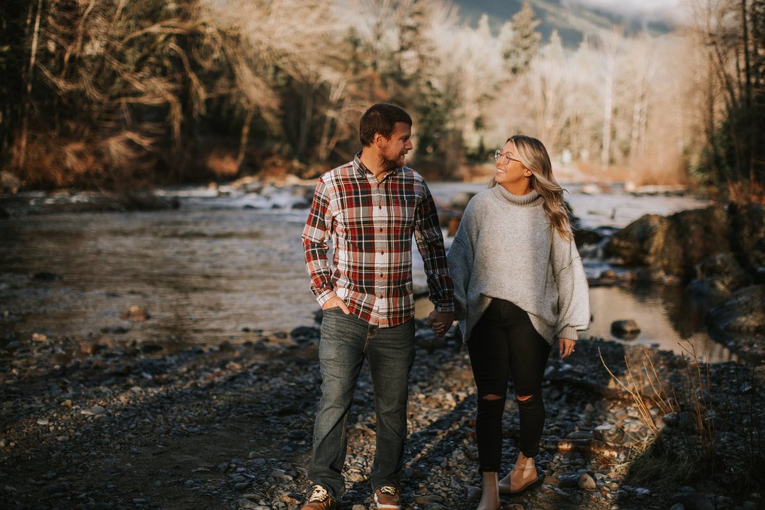 Couple embracing on the riverbank during golden hour