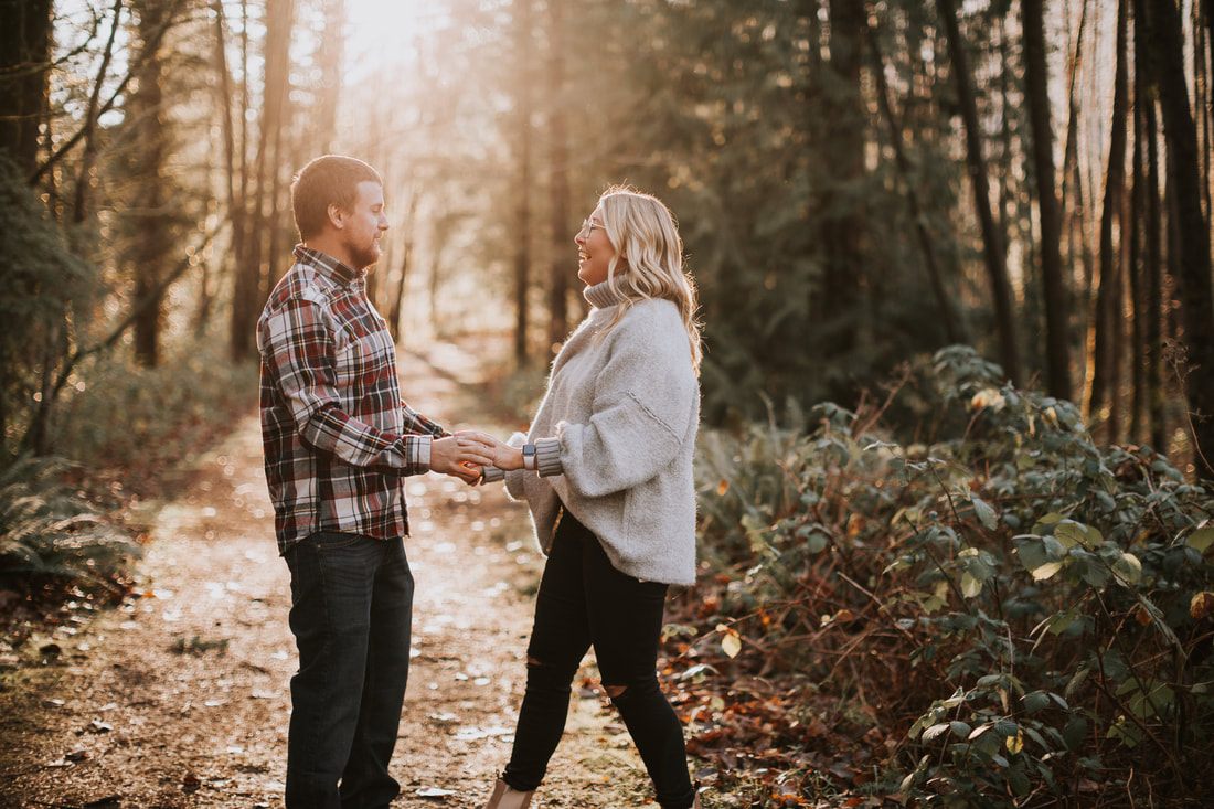 Couple walking hand in hand along the riverbank at golden hour