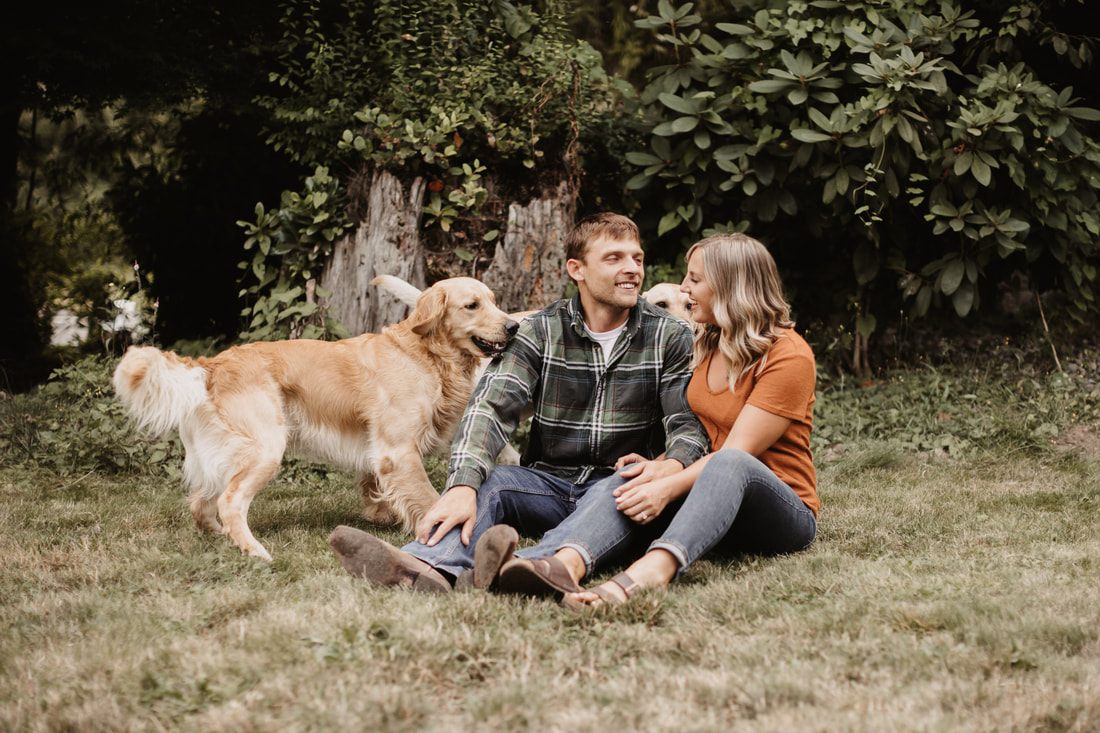 Engaged couple sitting with their dog in the farmyard
