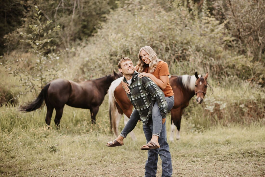 Engaged couple leading a horse across the pasture