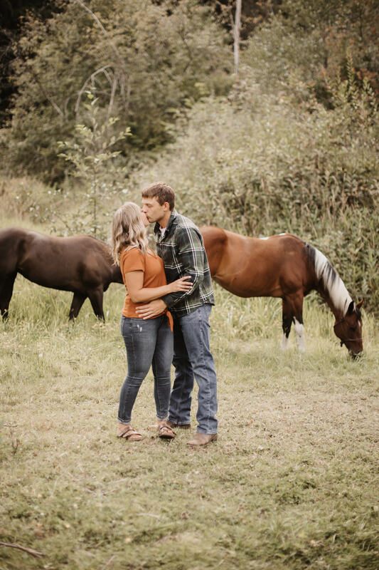 Engaged couple laughing together near a farm fence