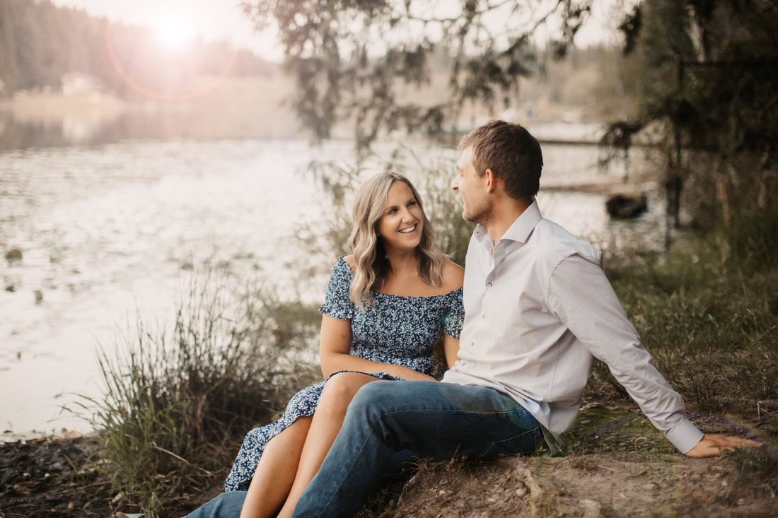 Engaged couple sharing a laugh in front of a red barn