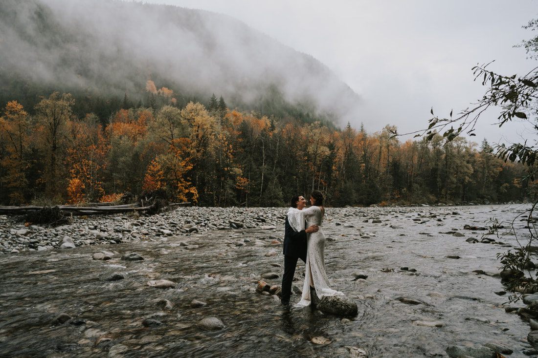 Couple embracing outside an A-frame cabin in the rainy Pacific Northwest
