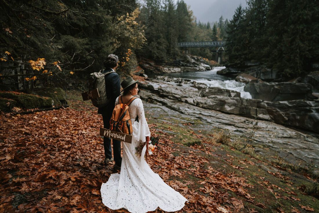 Couple sharing an umbrella during their rainy A-frame cabin elopement
