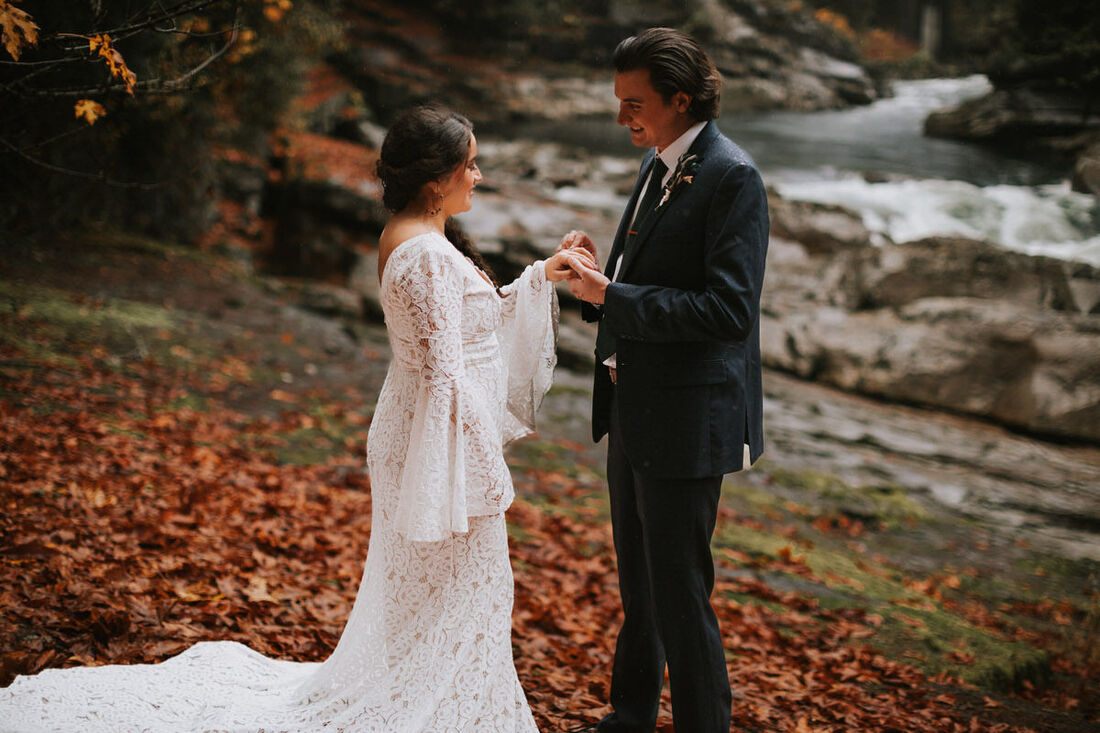 Moody portrait of a bride and groom in front of misty PNW trees