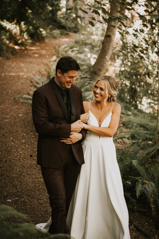The bride and groom posing among the vines surrounded by dark, moody florals