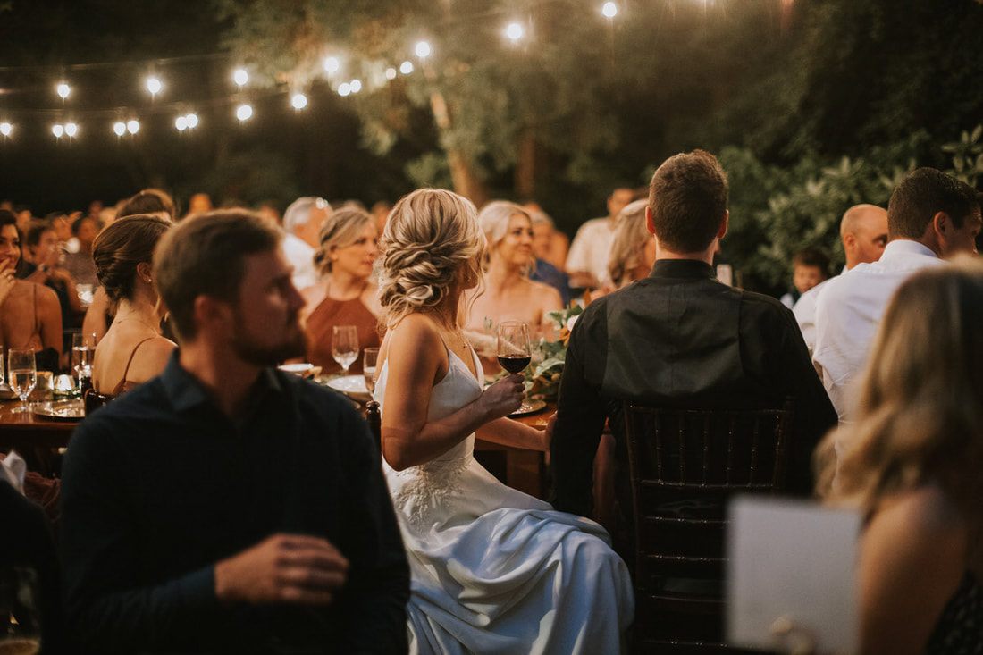 Katie and Alex walking through the vineyard surrounded by dark, moody florals