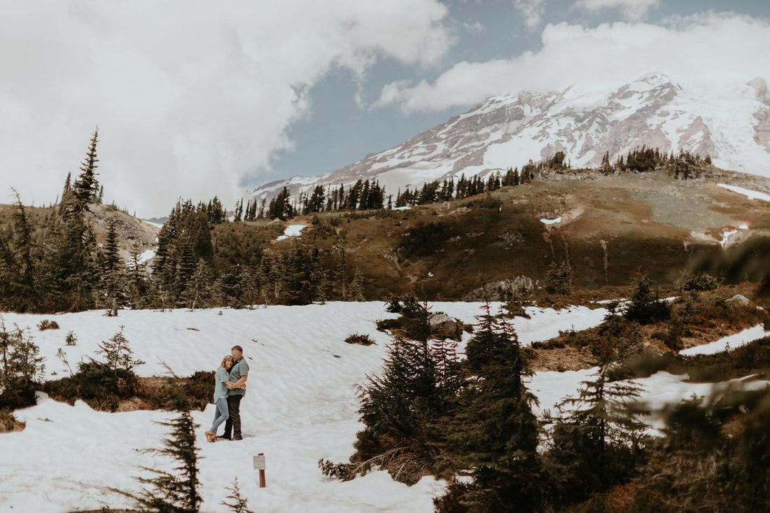 Couple posed together with dramatic mountain scenery behind them