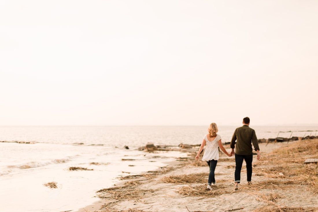 Wide shot of the couple and their dogs walking along Sullivan's Island beach