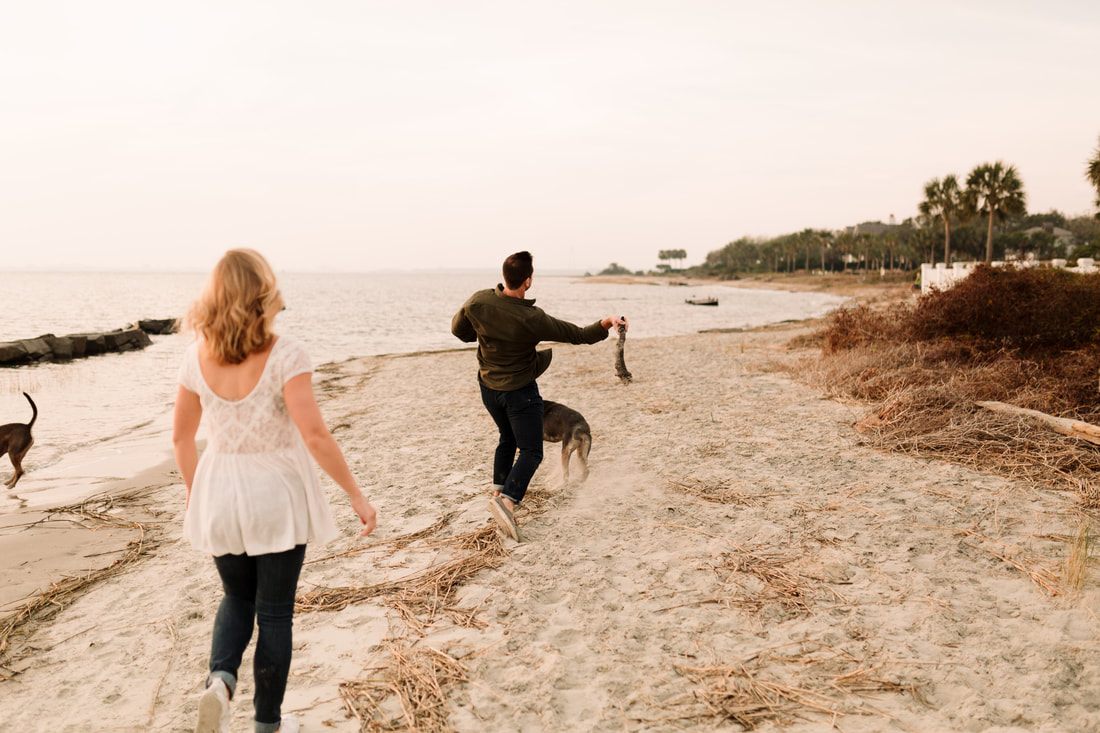 Wide landscape shot of the couple silhouetted against the Charleston Harbor sunset