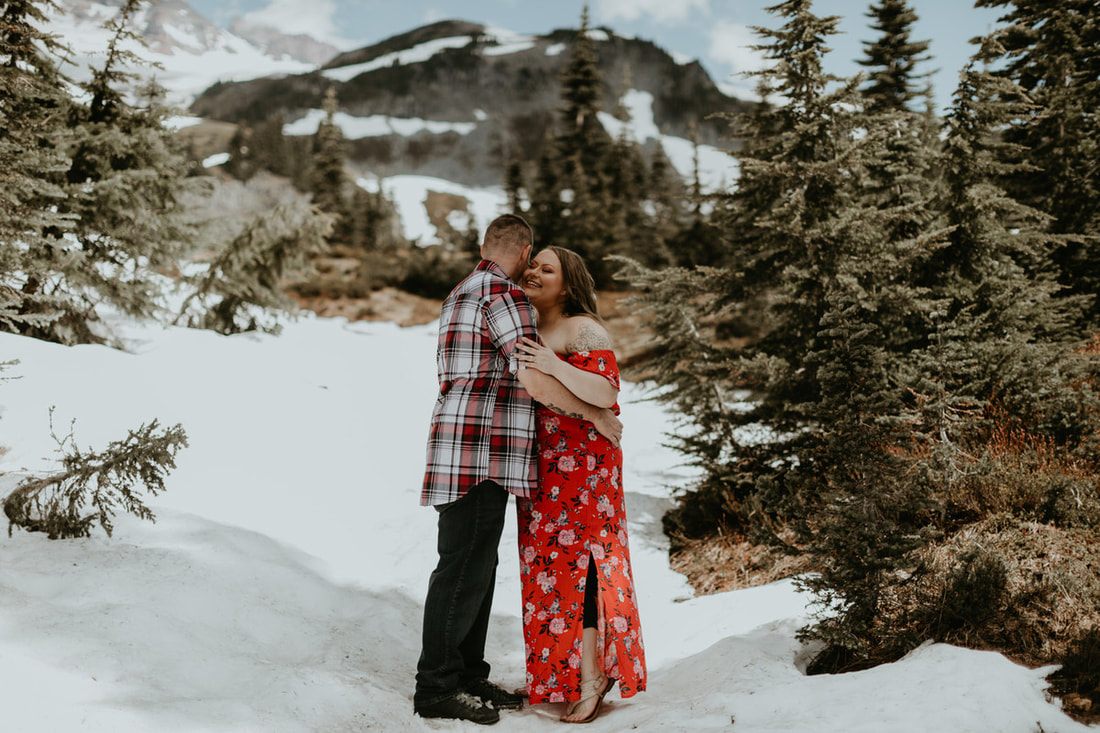 Engaged couple walking through an open pasture near Mt. Rainier