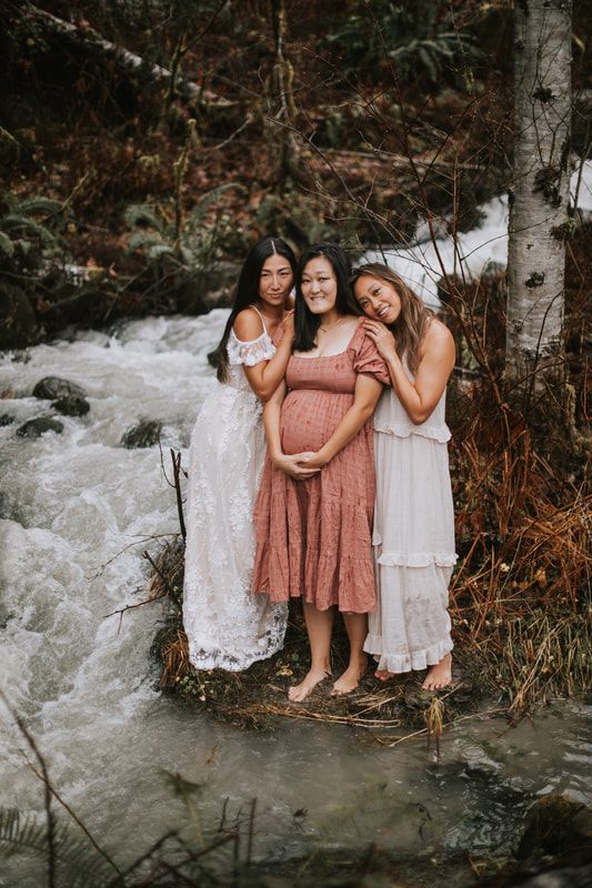 Maternity portrait of a mother-to-be standing in the rain near the cabin