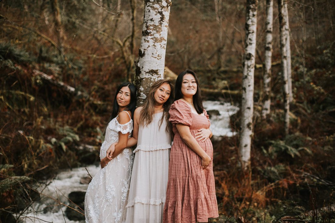 Three best friends embracing during their rainy-day maternity session