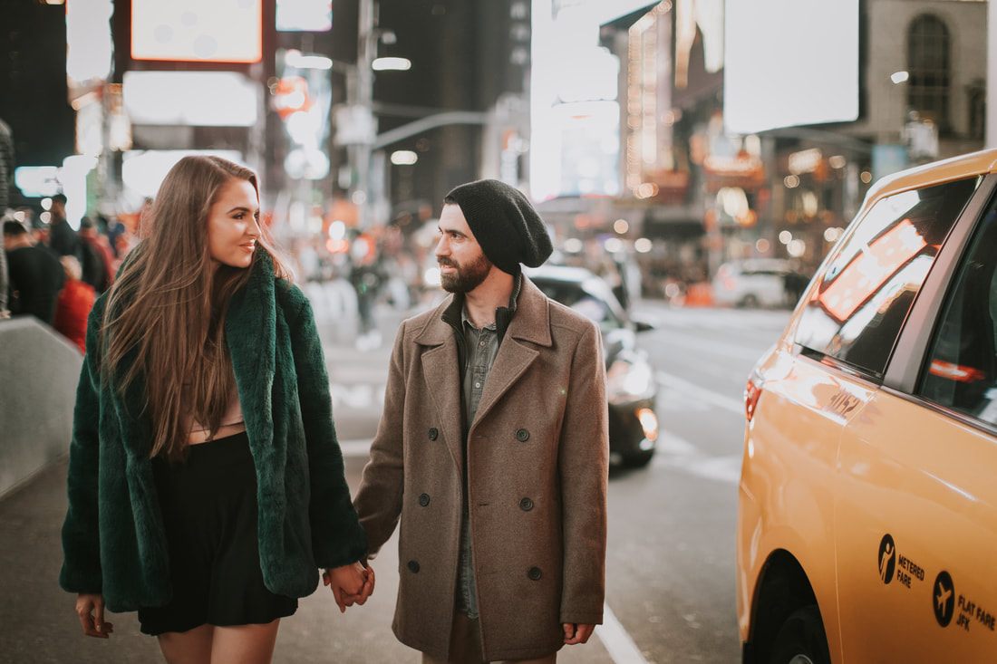Engaged couple embracing amid the neon glow of Times Square