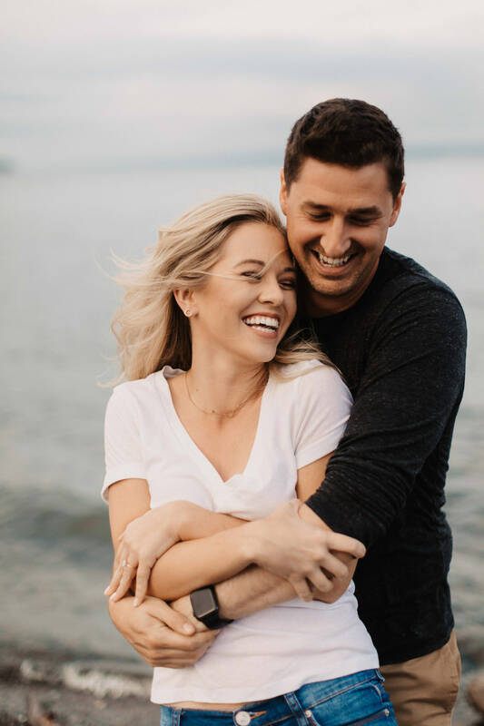 The couple laughing together on the rocky Bainbridge Island shoreline