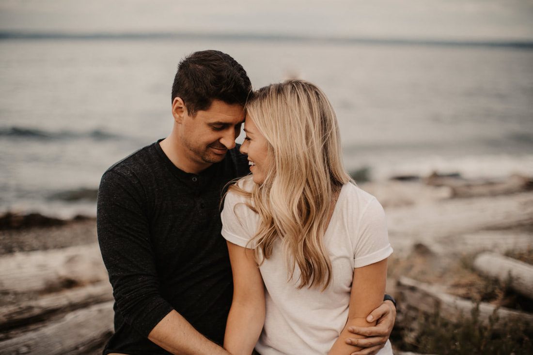 The couple embracing with the Seattle skyline in the distance