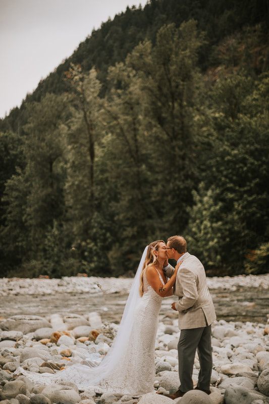 Groom carrying the bride playfully near the water's edge