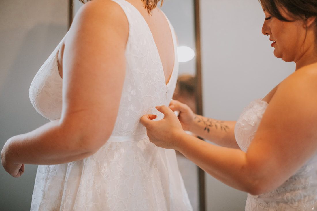 Two brides laughing together during golden hour portraits near the cabin, captured from another angle