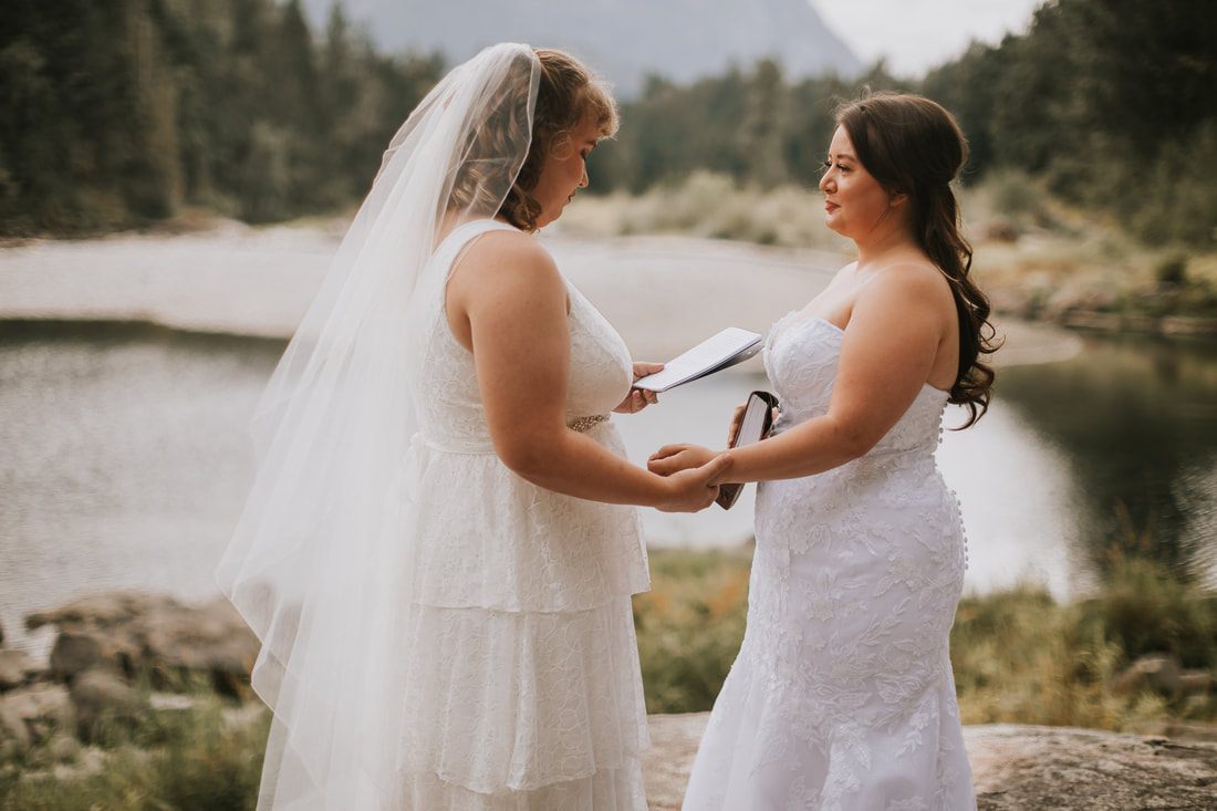Two brides laughing together during golden hour portraits near the cabin, later in the celebration