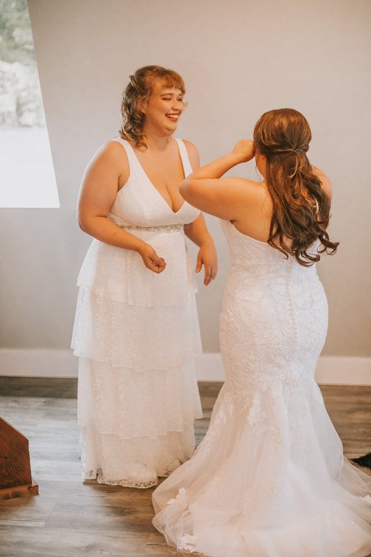 Two brides exchanging vows beneath the glass roof of the greenhouse ceremony, captured from another angle