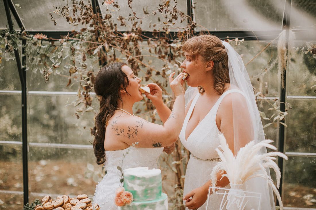 Two brides exchanging vows beneath the glass roof of the greenhouse ceremony, later in the celebration