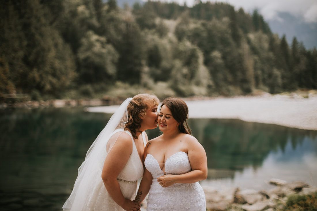 Two brides embracing on the porch of a Washington A-frame cabin