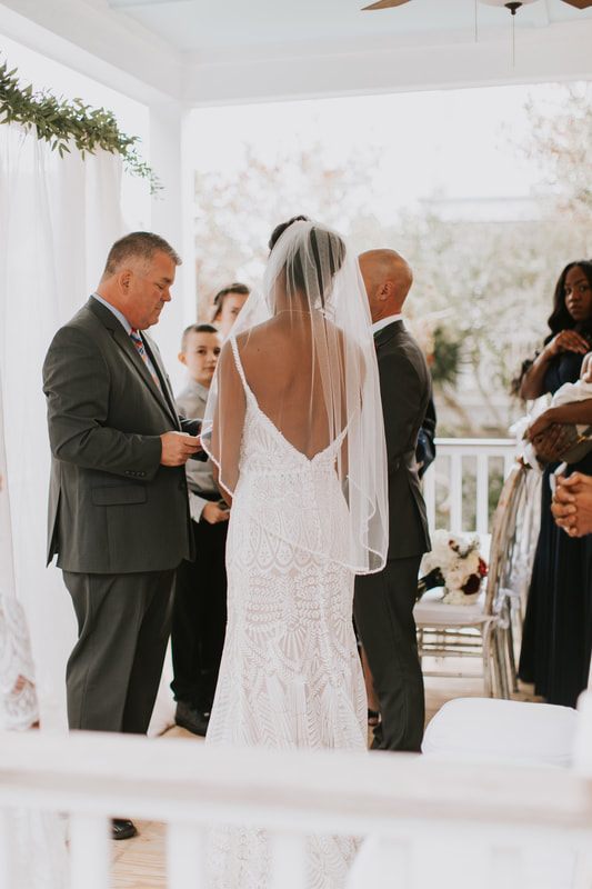 Close-up of the couple holding hands during their first look on the beach, back at the beach house
