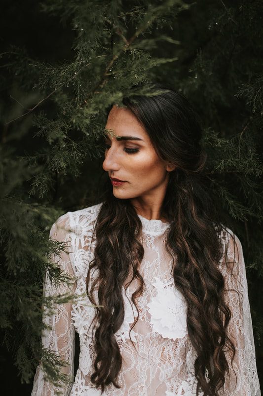 Anya seated on a fallen log in a forest bridal portrait