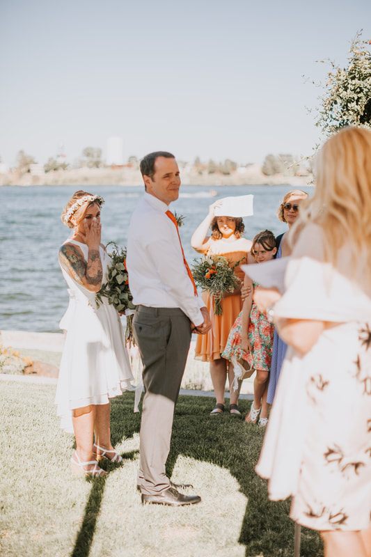 Bride and groom walking together along the lake during golden hour.
