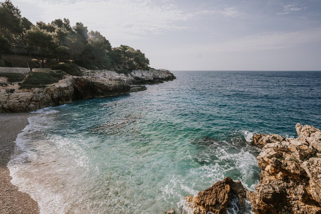 Photo of a rocky Adriatic shoreline with a ladder leading into the water in Croatia