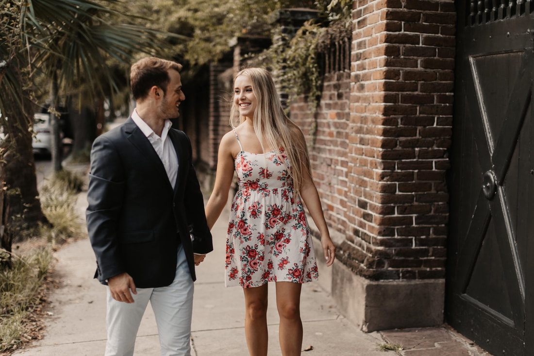 Alex embracing on the sidewalk beneath oak trees downtown