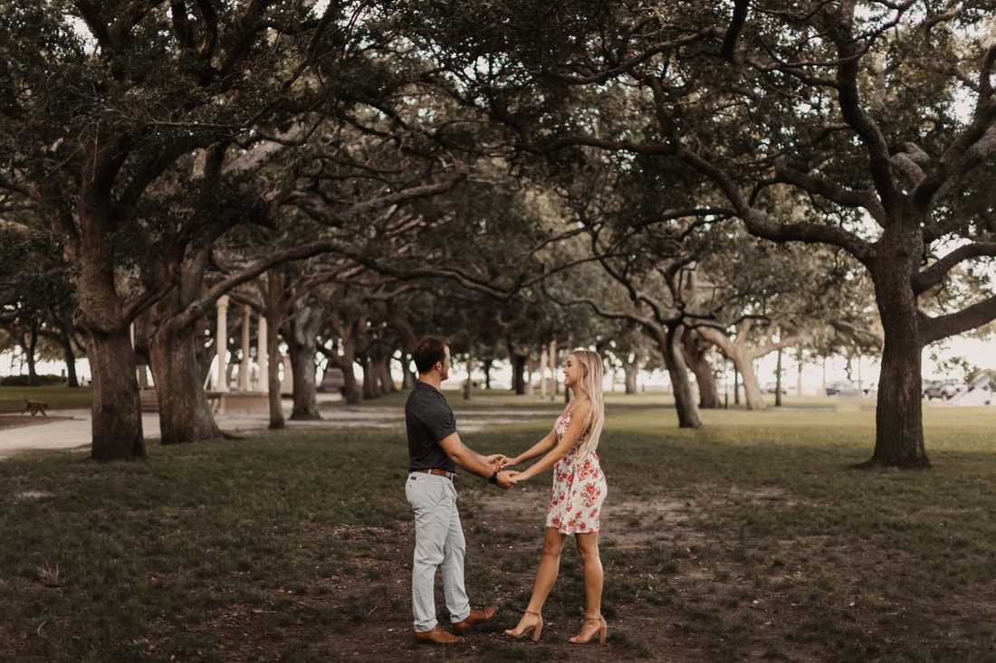 Alex and Jessica pausing for a portrait along a row of Charleston storefronts