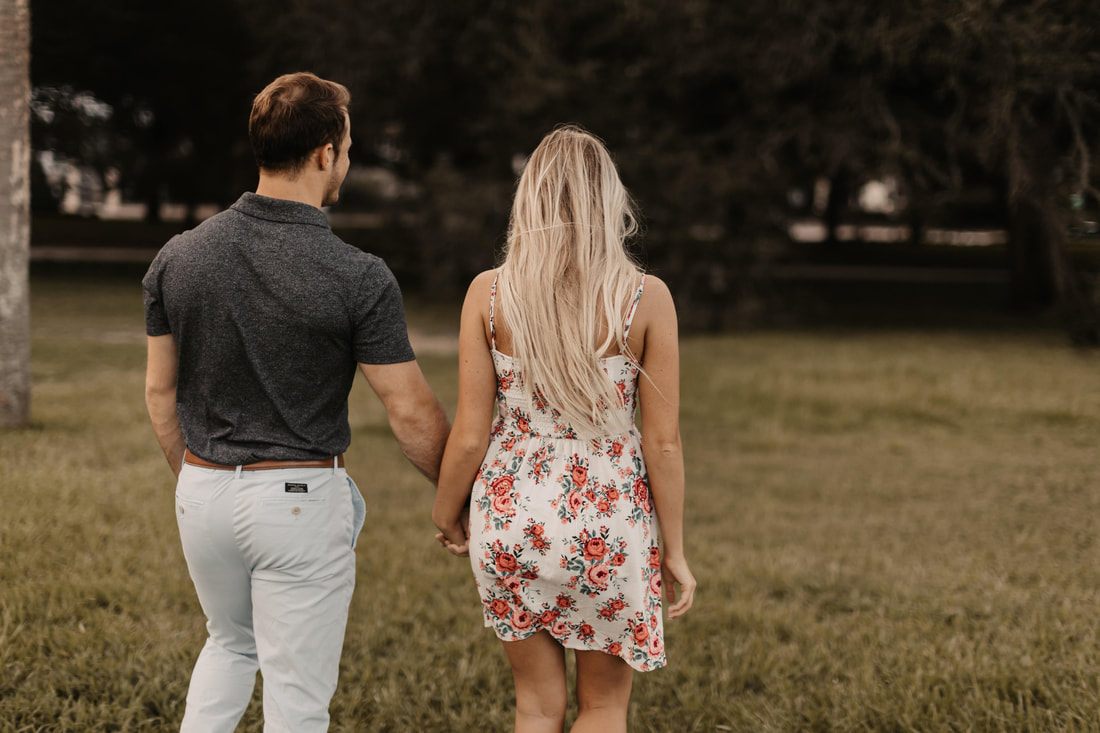 The engaged couple strolling past pastel storefronts in front of colorful pastel homes