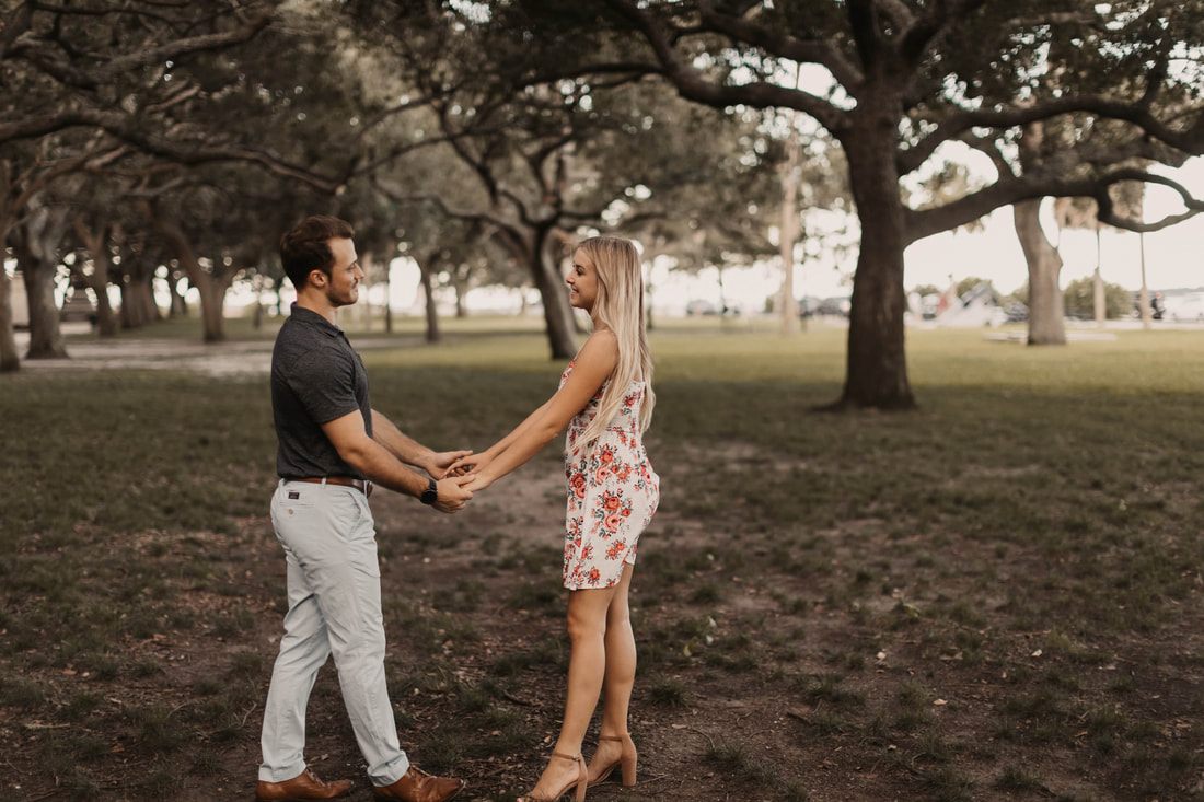 The engaged couple embracing on the sidewalk along a historic Charleston street