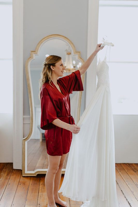 Bride stepping into her gown with help from a bridesmaid