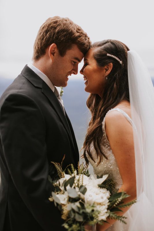 Cassandra and Charlie walk hand in hand with sweeping mountain views behind them.
