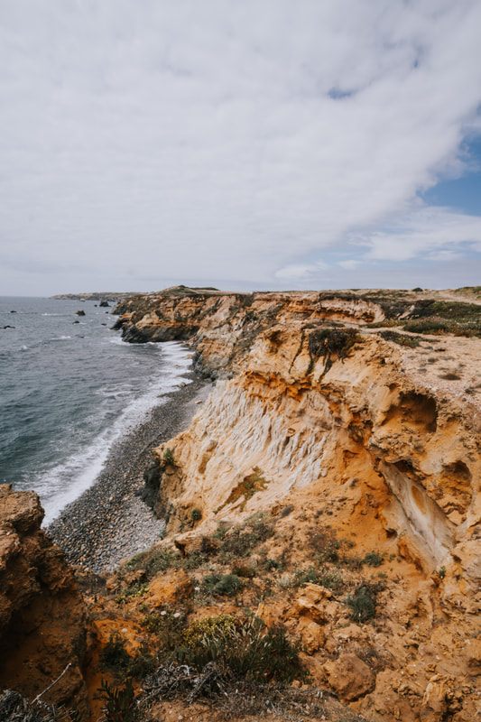 A sandy cove beach beneath grassy cliffs in southern Portugal