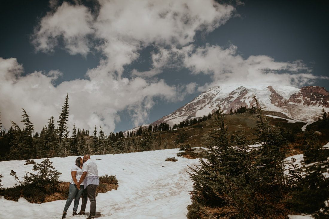 Tyeisha and Adam holding hands with dramatic mountain scenery behind them