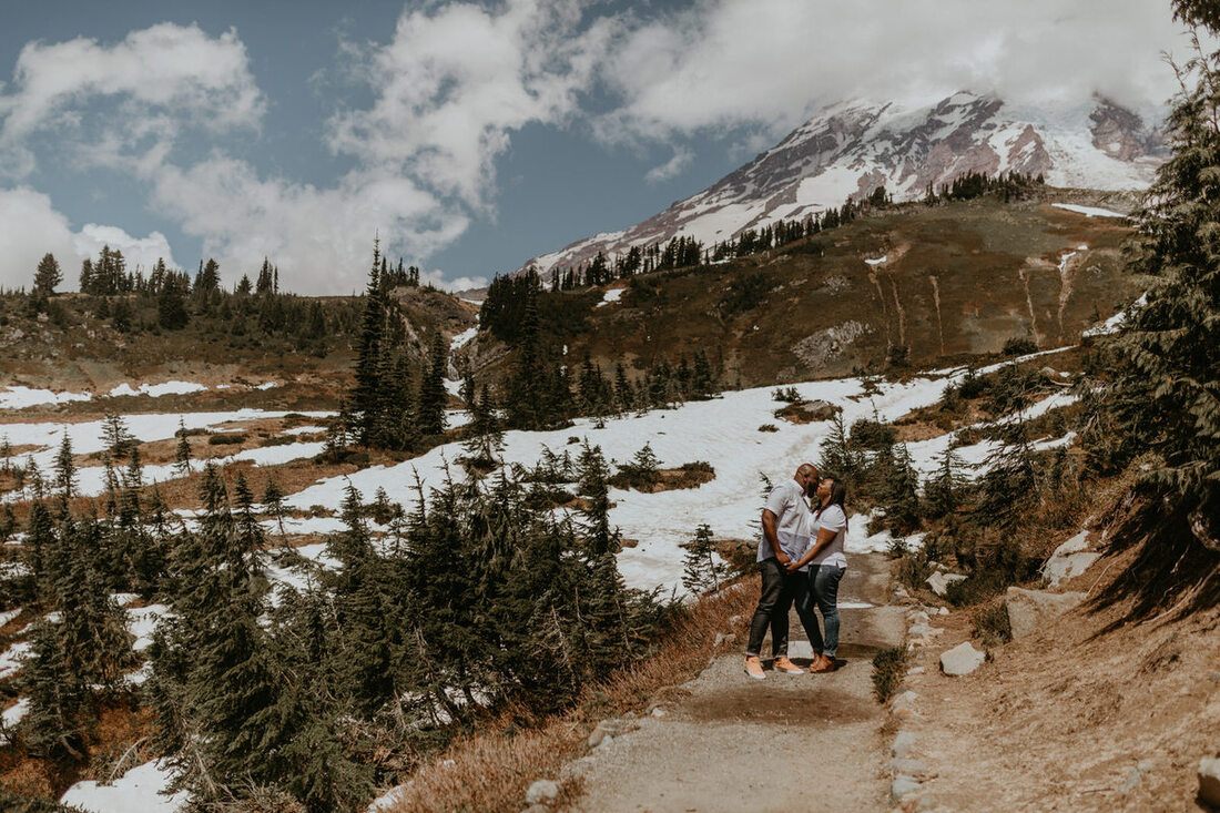 Wide shot of the couple with Mt. Rainier's glaciered peak rising behind them