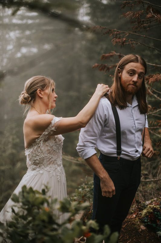 Bride's gown and bouquet detail against the moody, foggy forest backdrop.