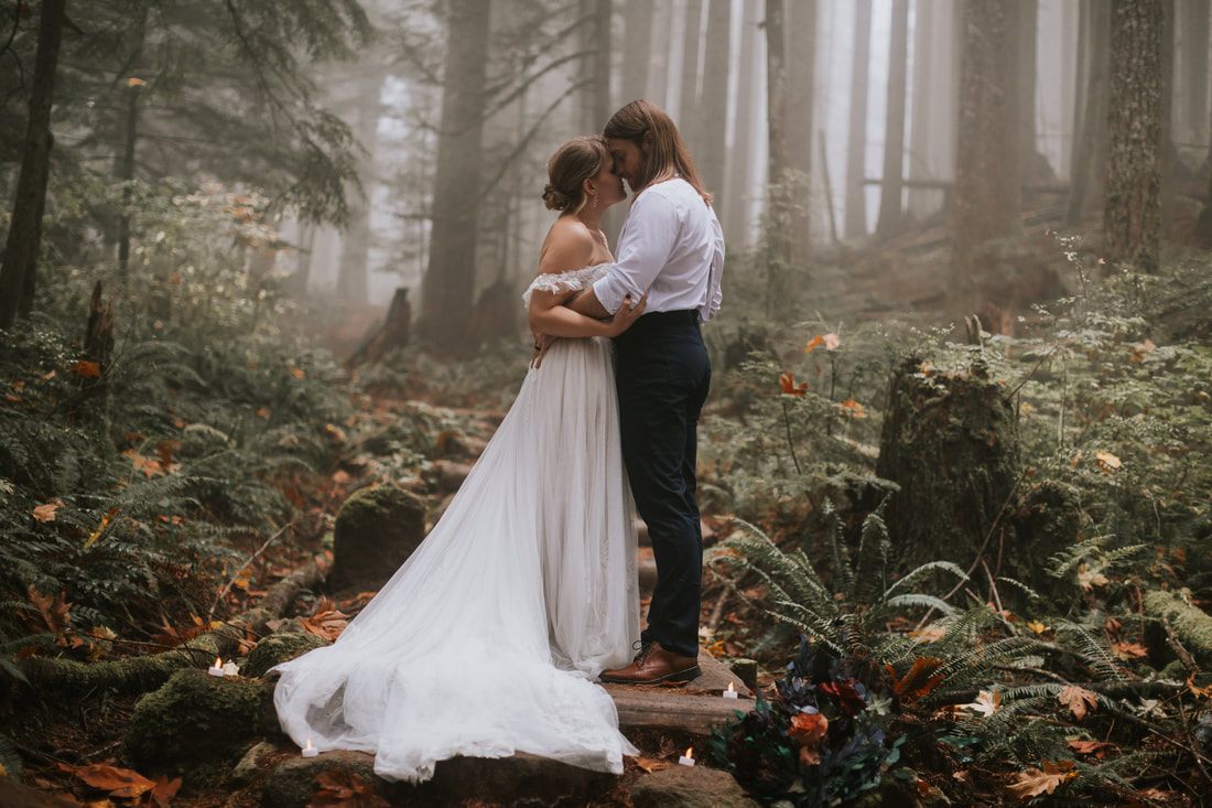 Silhouette of the couple walking through the foggy forest at dusk.