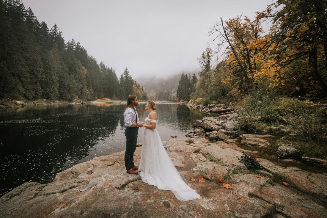 Bride's gown and bouquet detail against the moody, foggy forest backdrop.