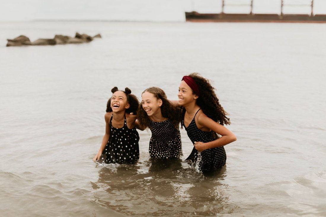 Deno Mickle embracing his daughters during a beach family photo session