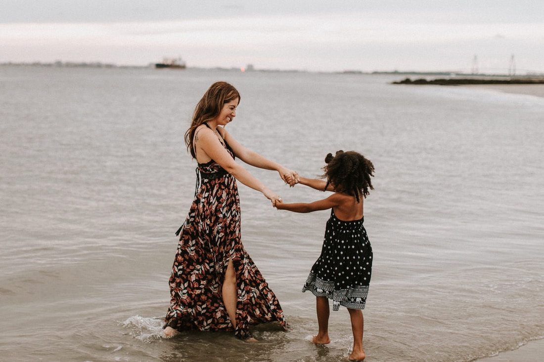 Deno Mickle carrying one of his daughters along the beach